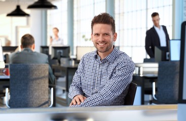 Casual man at desk in office smiling