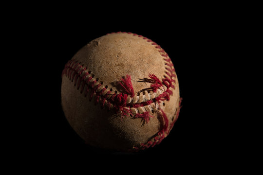 A used baseball on a black background