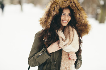 Young woman with a fur hood in the park on the snow