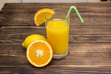 lemon juice and orange in the glass. Composition on wooden background. Fruit mix