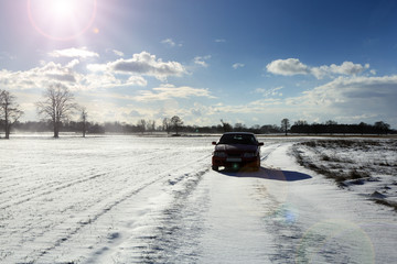 Samochód osobowy na zaśnieżonych polach w promieniach słońca. © Stanisław Błachowicz