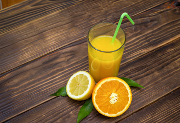 lemon juice and orange in the glass. Composition on wooden background. Fruit mix