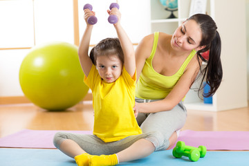Fototapeta premium family mother and child daughter are engaged in fitness, yoga, exercise at home or sport hall