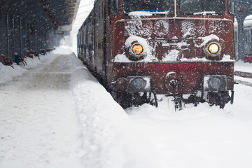 red locomotive train in railway station in winter time