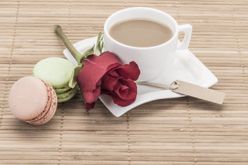 coffee and macaroons on wooden table decorated with red rose