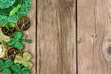 Obraz na płótnie Canvas St Patricks Day side border of shamrocks, gold coins and leprechaun hat over rustic wood