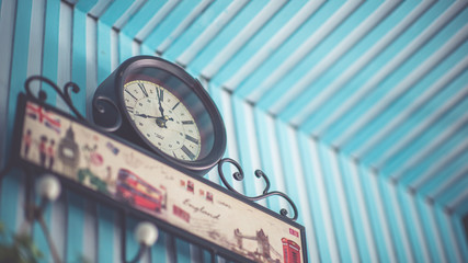 Retro wall clock on a vintage blue and white striped wallpaper background.
