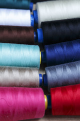 Group of bobbins of thread of various colors on a wooden table
