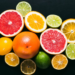 Fresh citrus stihli. Lemons, limes, grapefruit and orange on a black background
