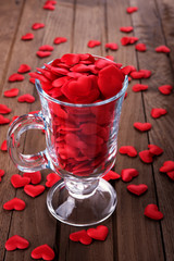 Glass with hearts on wooden table