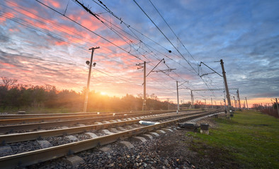 Railroad against beautiful sunny sky. Industrial landscape with railway station, blue sky and colorful red clouds at sunset . Railway junction in the evening. Heavy industry. Cargo shipping. Travel