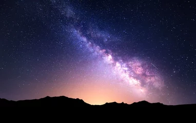 Foto auf Acrylglas Nachtlandschaft mit bunter Milchstraße und gelbem Licht an den Bergen. Sternenhimmel mit Felsen im Sommer. Schönes Universum © den-belitsky