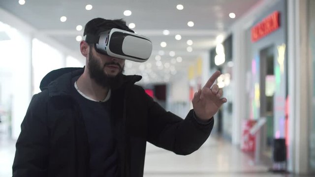 Young Man using virtual reality goggles in shopping center