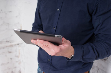 Office worker, freelancer, young man works through the tablet on the Internet. Hands holding a  closeup