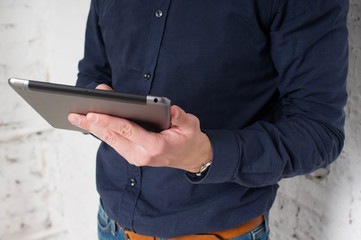 Office worker, freelancer, young man works through the tablet on the Internet. Hands holding a  closeup
