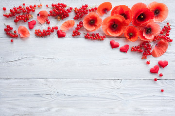Red flowers poppies, heart and berries on a wooden background