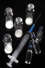 Medical syringe, vials with dry human hormone powder. Syringe with bare needle, medical bottles are...