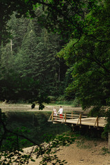Fototapeta premium Look from afar at lovely couple standing on wooden porch over mo