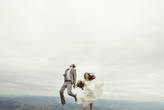 happy gorgeous bride and stylish groom jumping and having fun, b