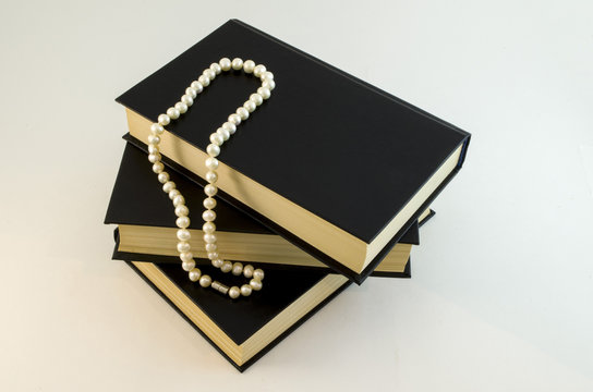 White pearls necklace on black. Books and pearls.