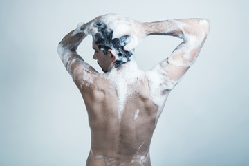 Naked young man covered with soap