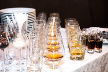 Glasses with different kinds of alcohol stand served in rows on