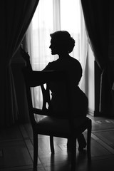 Silhouette of a woman sitting on soft chair and watching herself