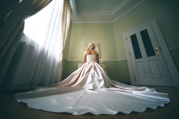 Bride in long ivory wedding gown sits before toilet table
