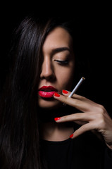 Portrait of the beautiful elegant girl smoking cigarette on black background.