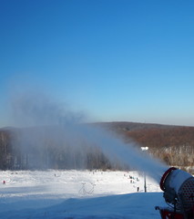 Snow gun producing fresh snow on sunny day