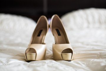 Luxurious beige shoes with open toes stand on soft blanket