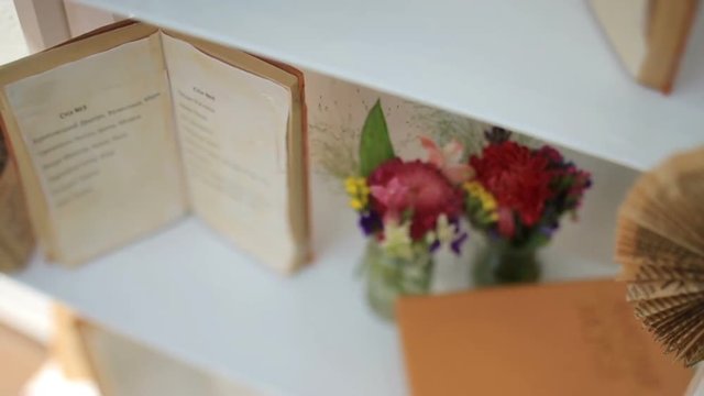 White shelf decorated with red flowers and old books