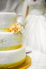 Wedding cake decorated with glaze flowers and yellow ribbons sta