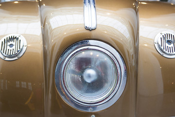 Central headlight detail on a goldenrod classic car