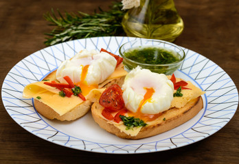 Crispy toast with poached egg, cheese, peppers, tomatoes, souse on a plate on a dark wooden background. Close up