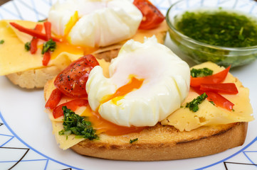 Crispy toast with poached egg, cheese, peppers, tomatoes, souse on a plate. Close up