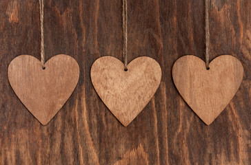 Three Wooden Brown Heart With Rope On Wooden Background Close Up.