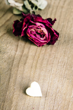 dried rose and chocolate heart on a wooden table, copy space