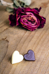 dried rose and two chocolate hearts on a wooden table, copy space