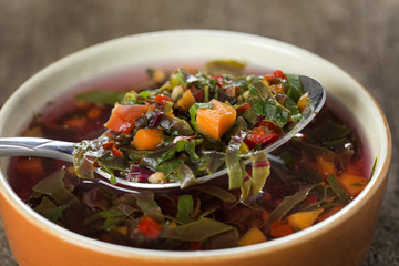East Europe soup or red borscht in bowl with spoon over wood