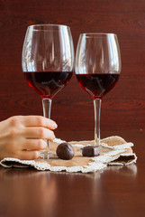Two glasses of wine on a wooden table. Candies. Hands.