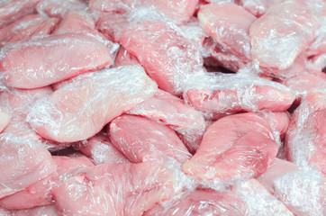 Pile of raw chicken meat in plastic wrap