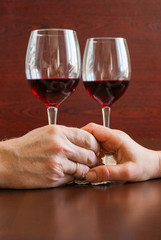 Two glasses of wine on a wooden table.  Hands.