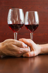 Two glasses of wine on a wooden table.  Hands.