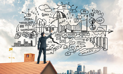 Rear view of businessman on house roof drawing his new business 