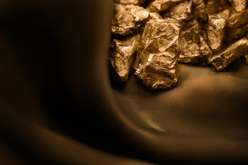 Golden nuggets on chocolate silk cloth with soft light