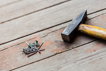 Hammer and nails on wood floor background. Close-up perspective view with blurred background