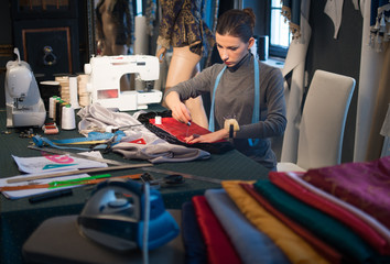 The dressmaker sews clothes of red and black satin