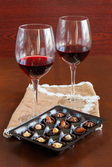 Two glasses of wine on a wooden table.  Candies.