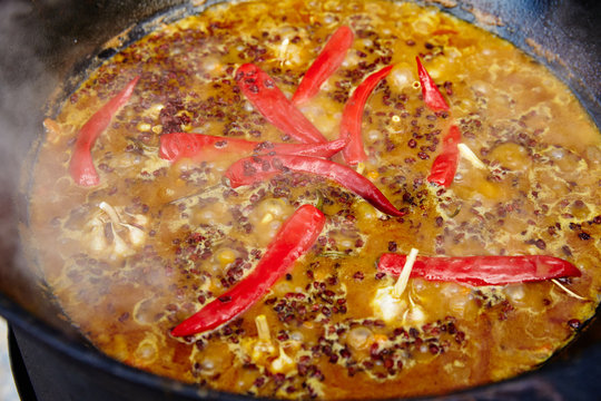 National Uzbek dish pilaf, pilaw, plov, rice with meat in big pan. Cooking process in a cauldron on fire. 
Preparation stages. pour out rice, Add waters, red pepper and the whole garlic